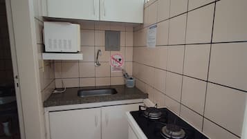 A small kitchen with a sink, stove, and a microwave.