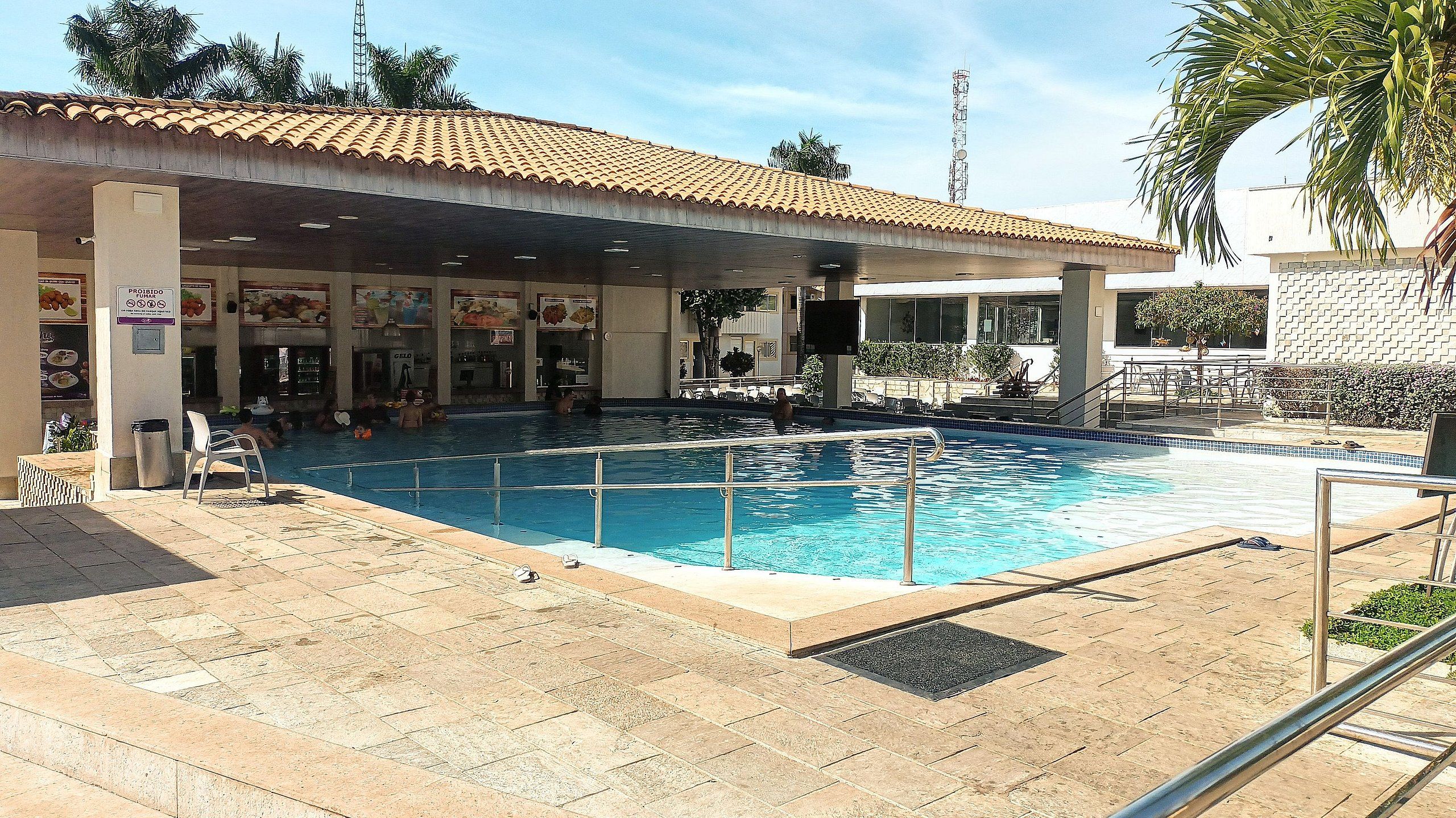 Una piscina con techo de azulejos, un basurero y un cartel.