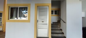 Eine Treppe mit Handlauf, ein Fenster mit Vorhängen und eine Tür mit einem weißen Rollo.