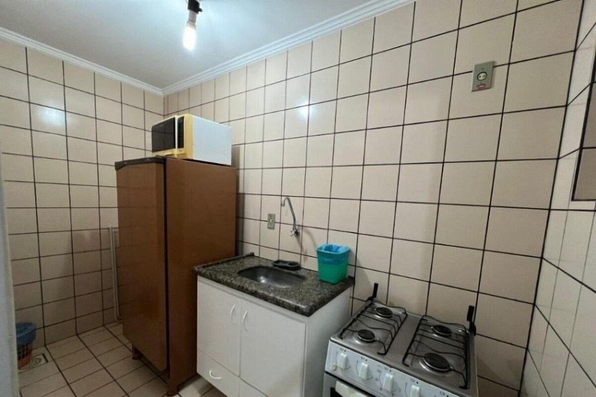 Eine kleine Küche mit Kühlschrank, Spüle, Gasherd und Schränken.