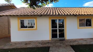 A single-story building with a tiled roof, a front door, and three windows.