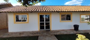 Um edifício térreo com telhado de telhas, porta frontal e três janelas.