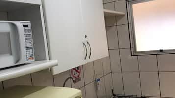Una cocina con armarios blancos, microondas, estufa a gas y fregadero.