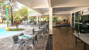 Un espace extérieur aménagé avec des tables et des chaises, une piscine et une table de ping-pong.