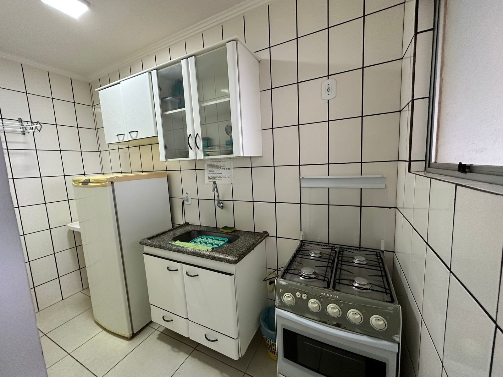 Uma cozinha compacta com armários brancos, um balcão pequeno e um fogão a gás.