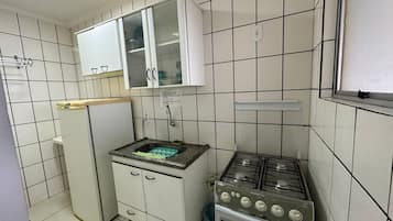 Uma cozinha compacta com armários brancos, um balcão pequeno e um fogão a gás.