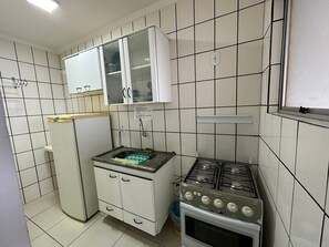 Une cuisine compacte avec des meubles blancs, un petit plan de travail et une cuisinière à gaz.