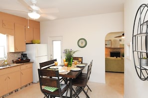 A compact kitchen with wooden cabinets, a dining table set for four, and a ceiling fan. - The Island House of Siesta (Sarasota)