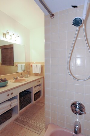 A bathroom with a sink, mirror, towel rack, shower, and patterned floor.