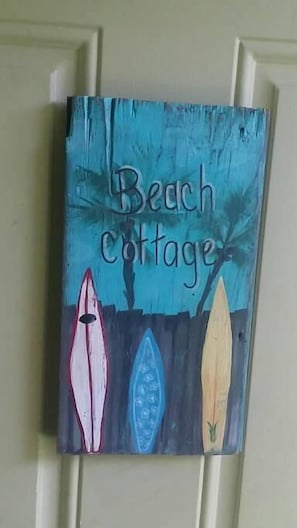 Pintura intitulada 'Beach Cottage' com três barcos estilizados.