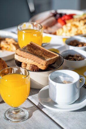 Un desayuno con tostadas, zumo de naranja y café.