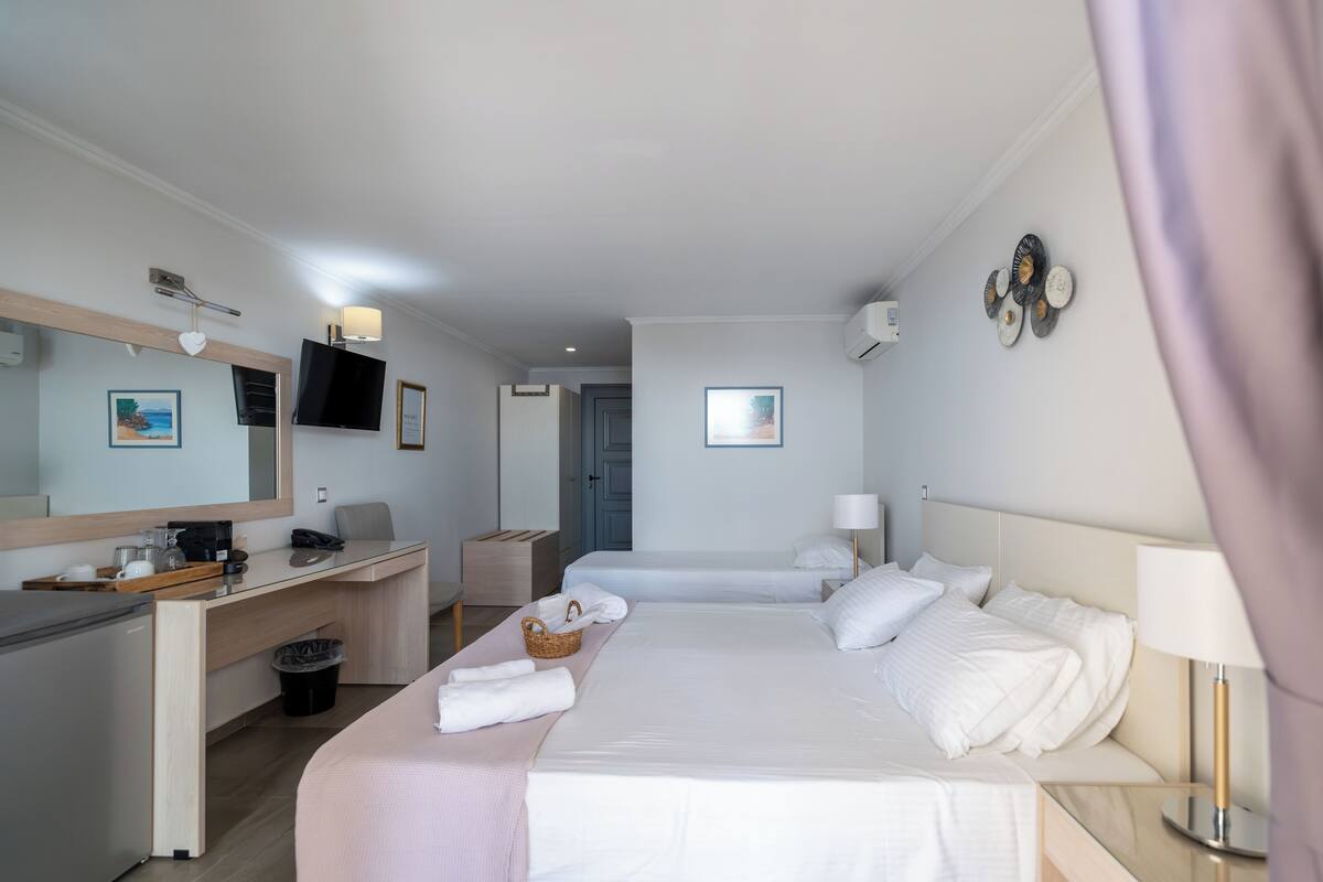 A hotel room with a bed, a desk, a chair, a TV, and a bathroom.