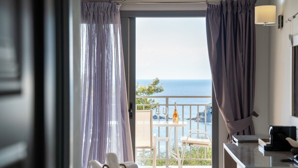 Habitación de hotel con balcón, cama, escritorio y vista al mar.