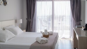 Una habitación de hotel con una cama bien hecha, una mesita de noche con lámpara y una ventana con cortinas.