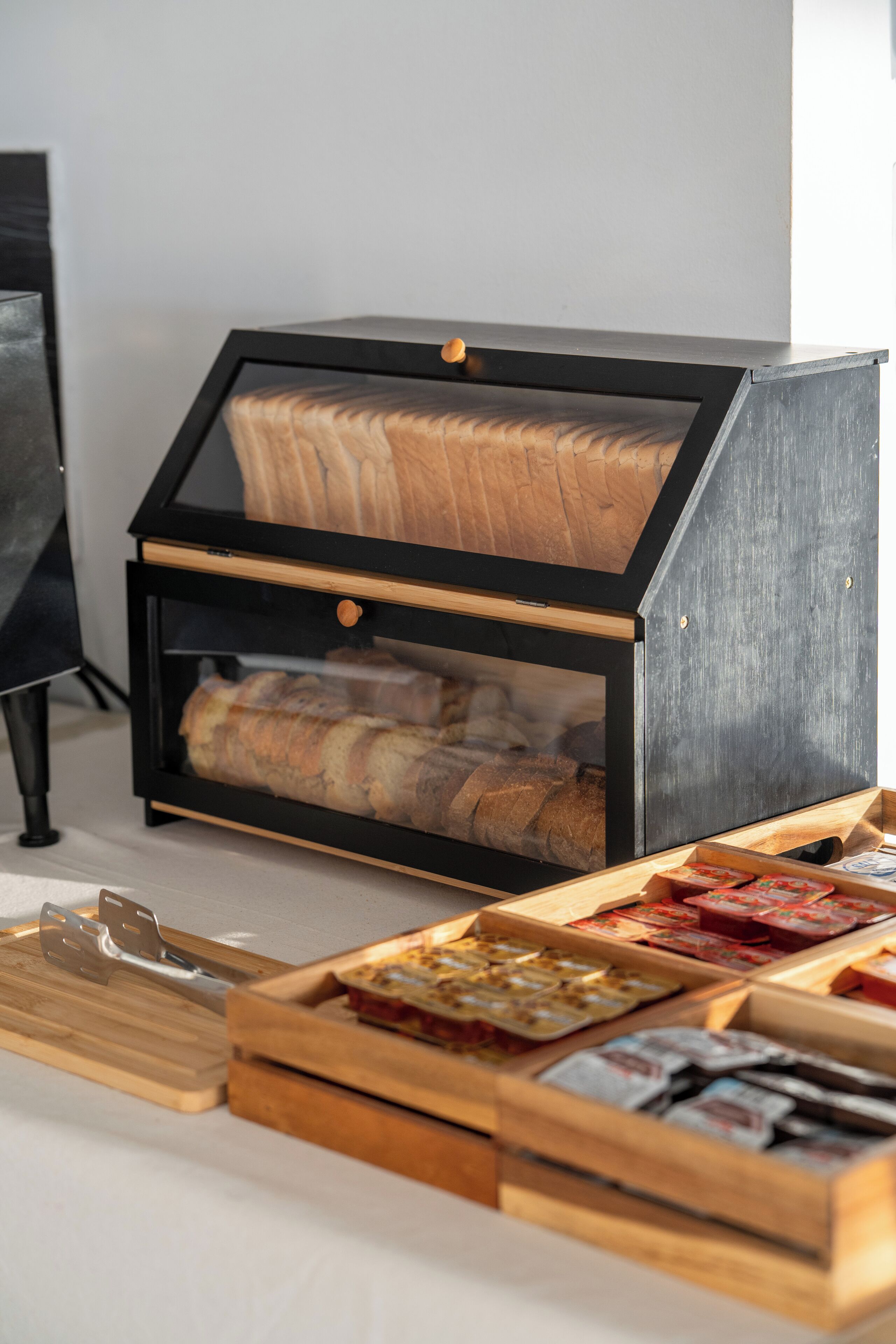 A bread display with a glass front and wooden interior, alongside a variety of packaged goods.