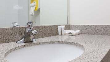 A bathroom sink with a modern faucet, a mirror, and a towel dispenser.