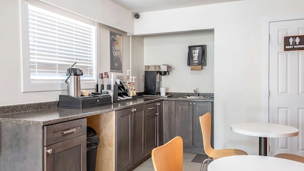 Una cocina moderna con una cafetera, un lavamanos y una zona de comedor con dos sillas.