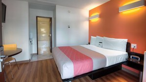 Habitación de hotel con cama, mesita de noche y una pequeña mesa con sillas.
