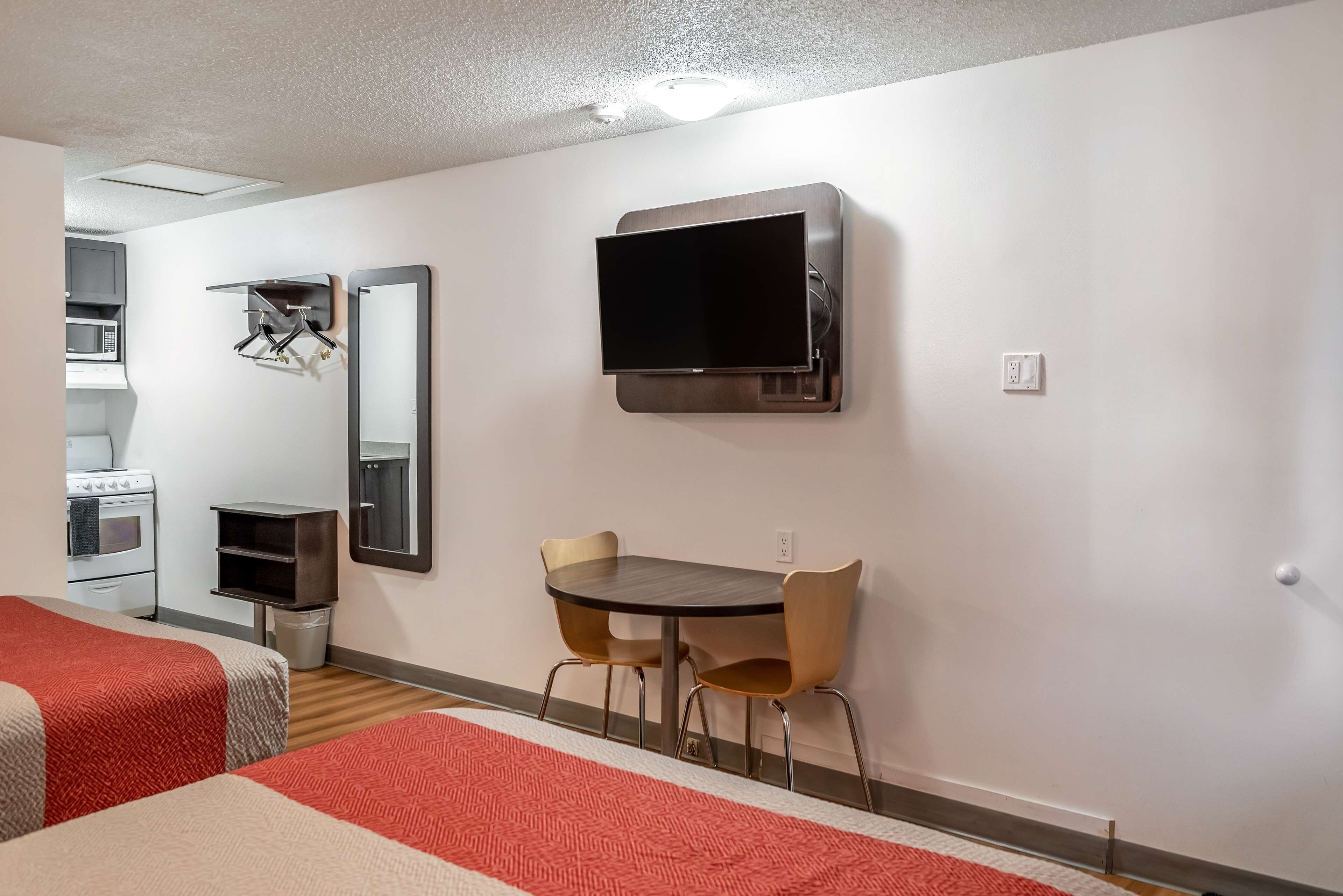 Camera d'albergo con due letti, un tavolo da pranzo con sedie, una TV a parete, un forno a microonde e un angolo cottura.