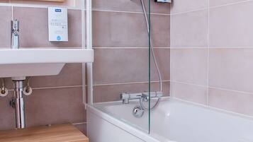 A modern bathroom with a glass-enclosed shower, a white bathtub, and a wooden vanity.