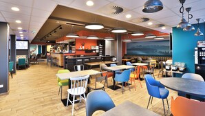 Un café moderne doté de plusieurs espaces de détente, comprenant des tables et des chaises, et d’un comptoir de bar en arrière-plan.