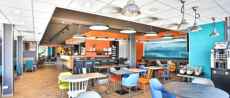 A modern cafe with multiple seating areas, including tables and chairs, and a bar area with a coffee machine.