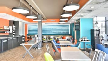 A modern cafe with multiple seating areas, including tables and booths, and a large mural on the back wall.