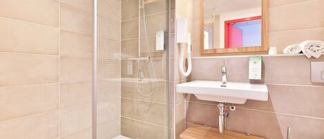 Un baño moderno con ducha de vidrio, lavamanos blanco y tocador de madera.