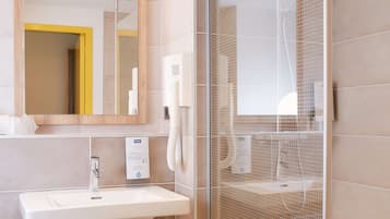A modern bathroom with a glass shower enclosure, a sink with a mirror, and a wooden bench.