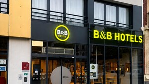 Un hôtel de type « bed and breakfast » avec une enseigne jaune bien visible, une grande entrée en verre et un comptoir d’accueil facilement identifiable.