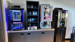 Un mini-bar équipé d’une machine à café, d’un présentoir à verres et d’un distributeur d’eau.