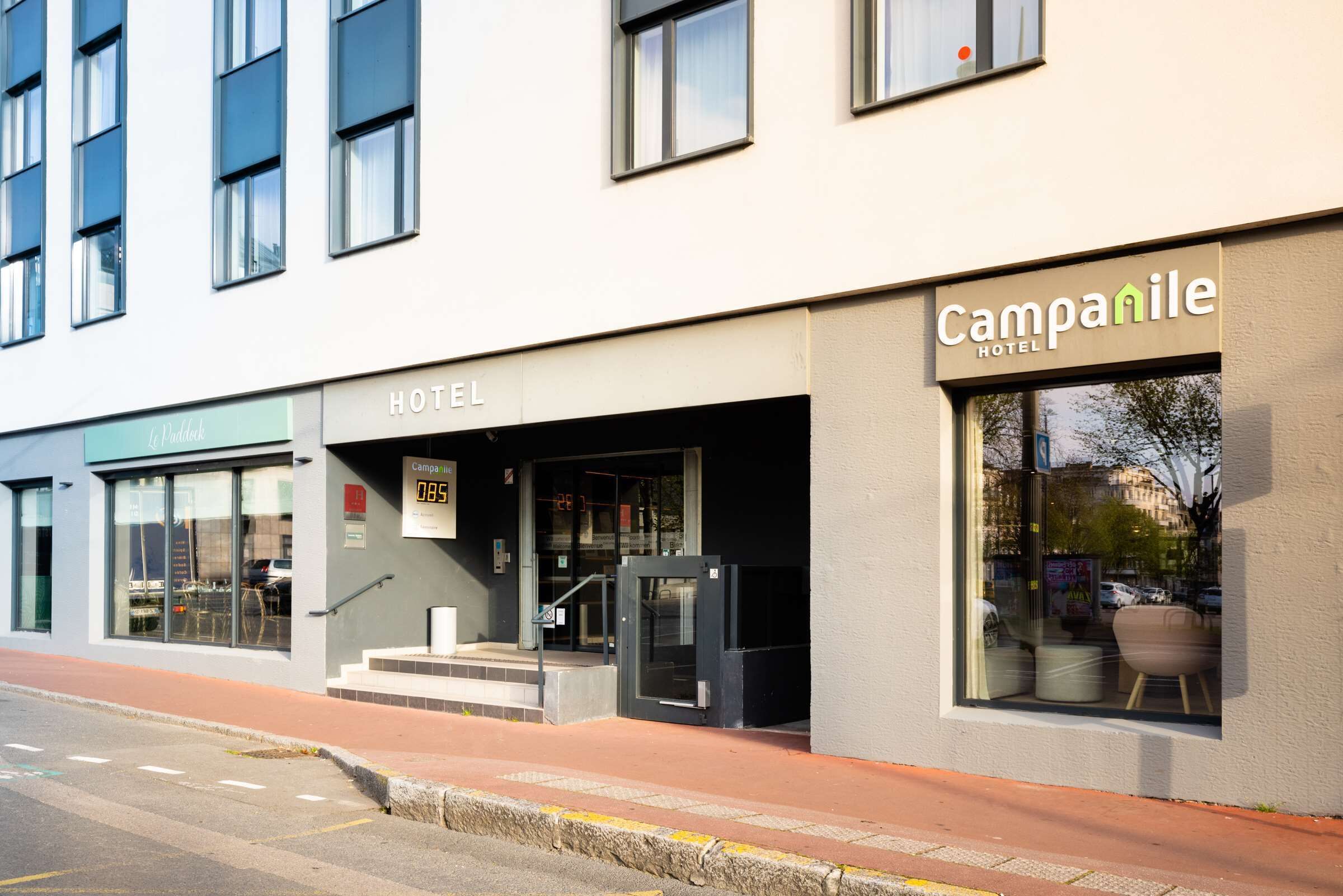 A hotel with a modern facade, a digital display showing room availability, and a clear entrance with steps leading up to the door.