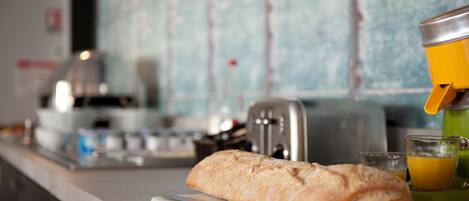 A kitchen counter with a loaf of bread, a toaster, and a glass of orange juice.
