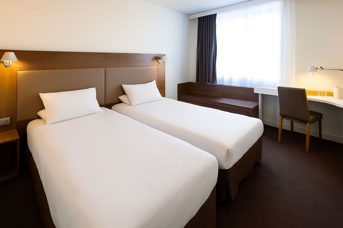Habitación de hotel con dos camas, un escritorio y una silla.