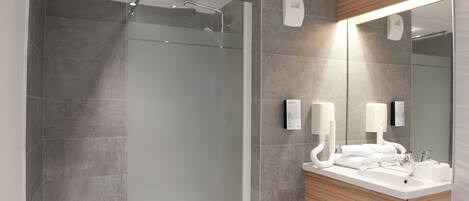 A modern bathroom with a glass-enclosed shower, a large mirror, and a wooden vanity with a sink.