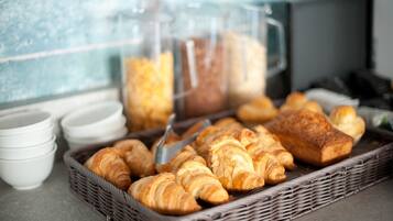 Un bufé de desayuno con cruasanes, pan y tazas de café.
