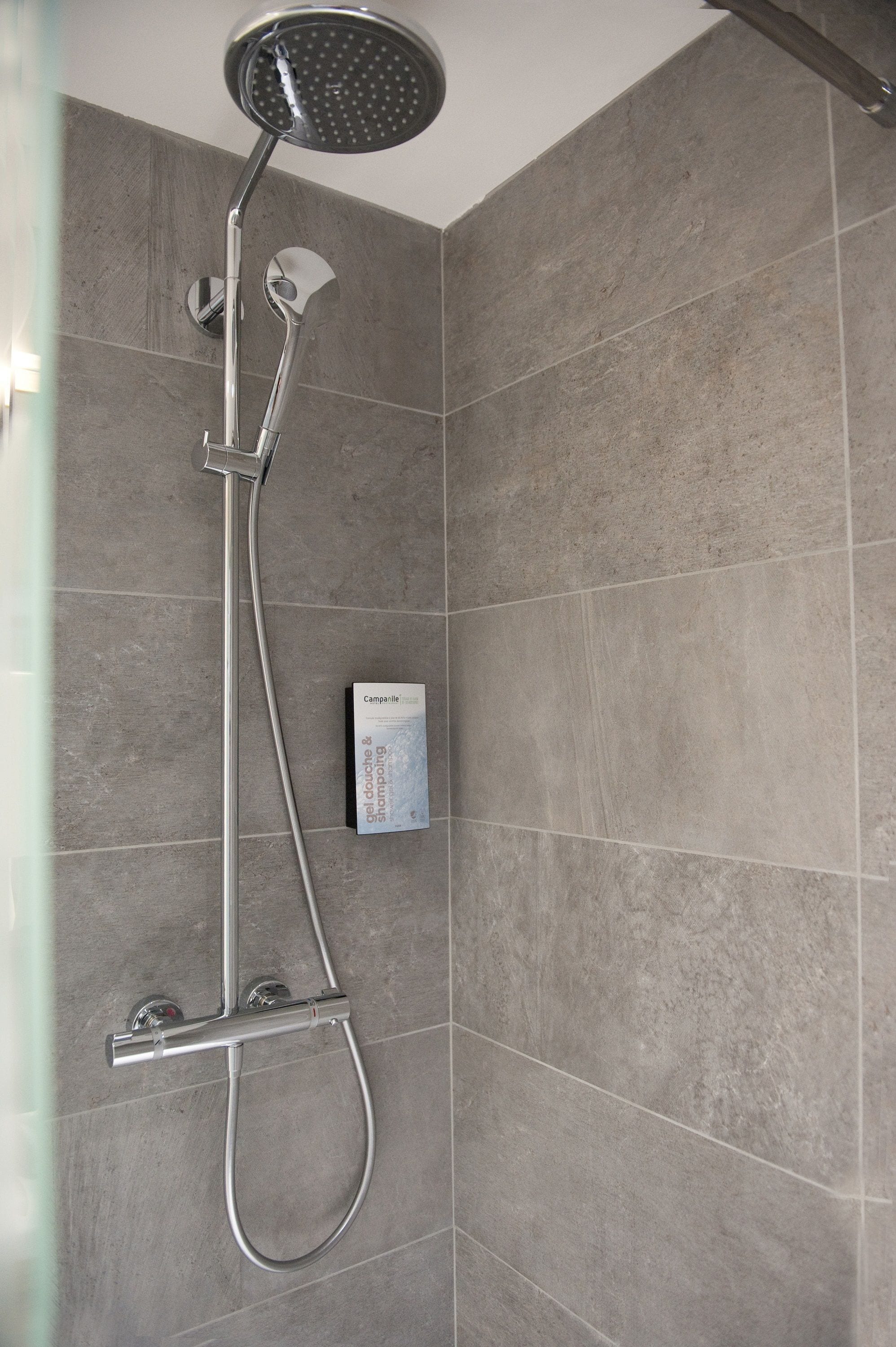 Ducha con cabezal de ducha manual y panel de control en la pared.