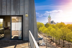 Un edificio moderno con un amplio ventanal y una vista de un edificio histórico con una cúpula verde al fondo.