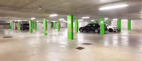 A multi-level underground parking garage with green pillars and clear signage.