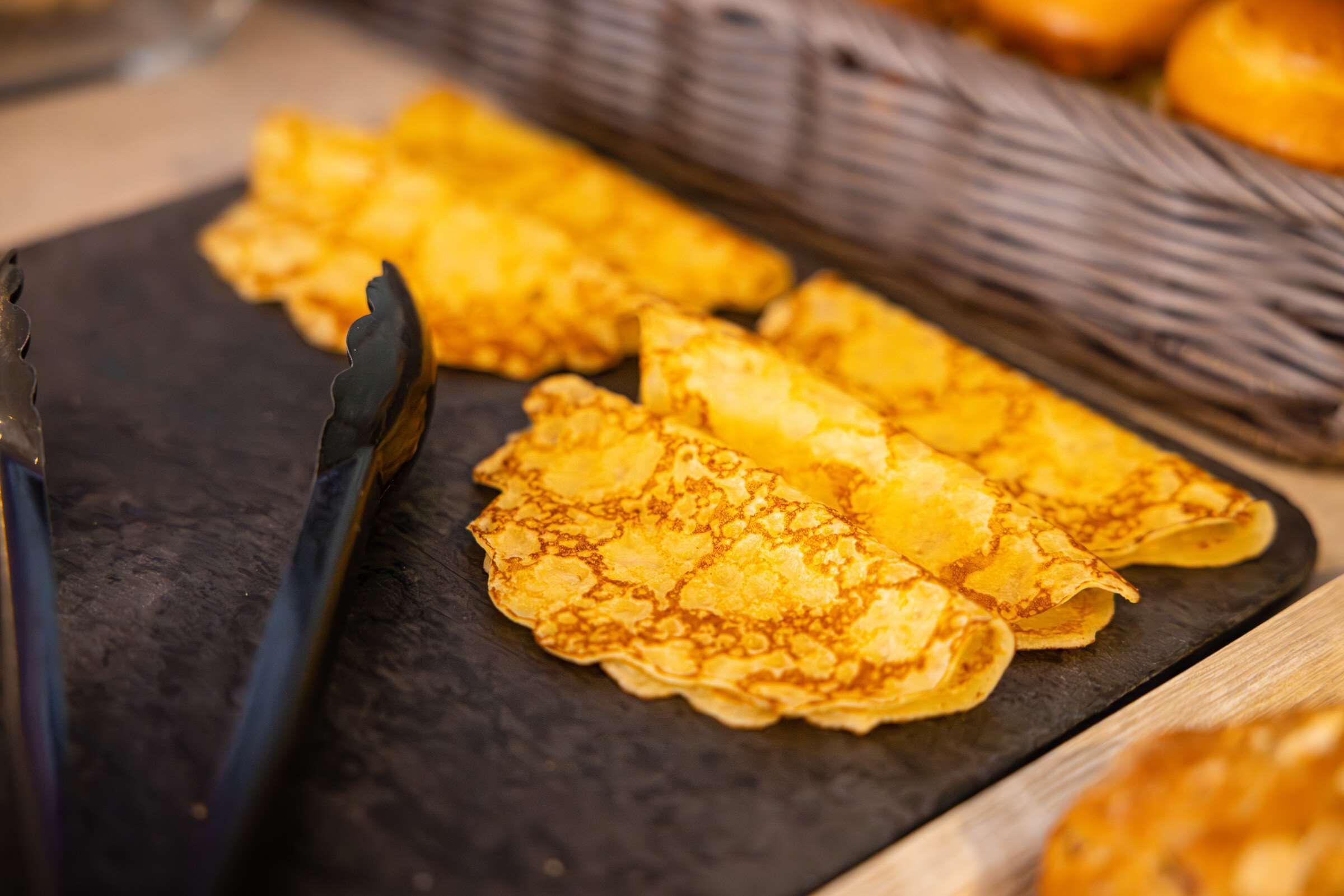 A close-up of golden-brown pancakes on a dark slate plate.