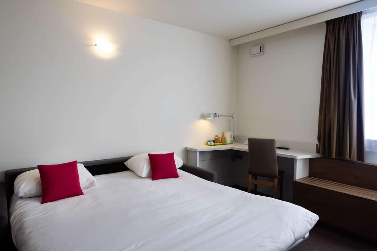 Relax in a serene space with a large bed, desk, and comfortable seating area.