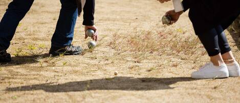 A person holding a ball and another person holding a can, both standing on a grassy field.