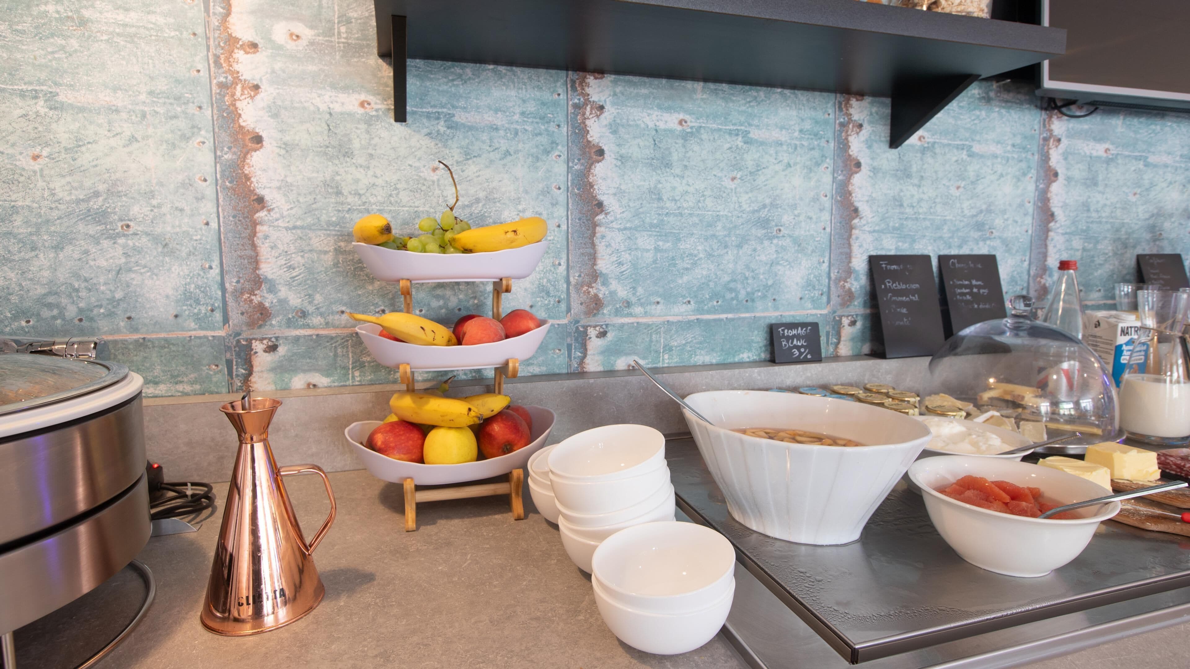 A breakfast buffet with fruits, cheeses, and dairy products.