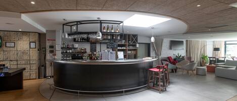 Un área de bar moderna con una barra curva, estantes con botellas y una zona de estar con sillas y un sofá.