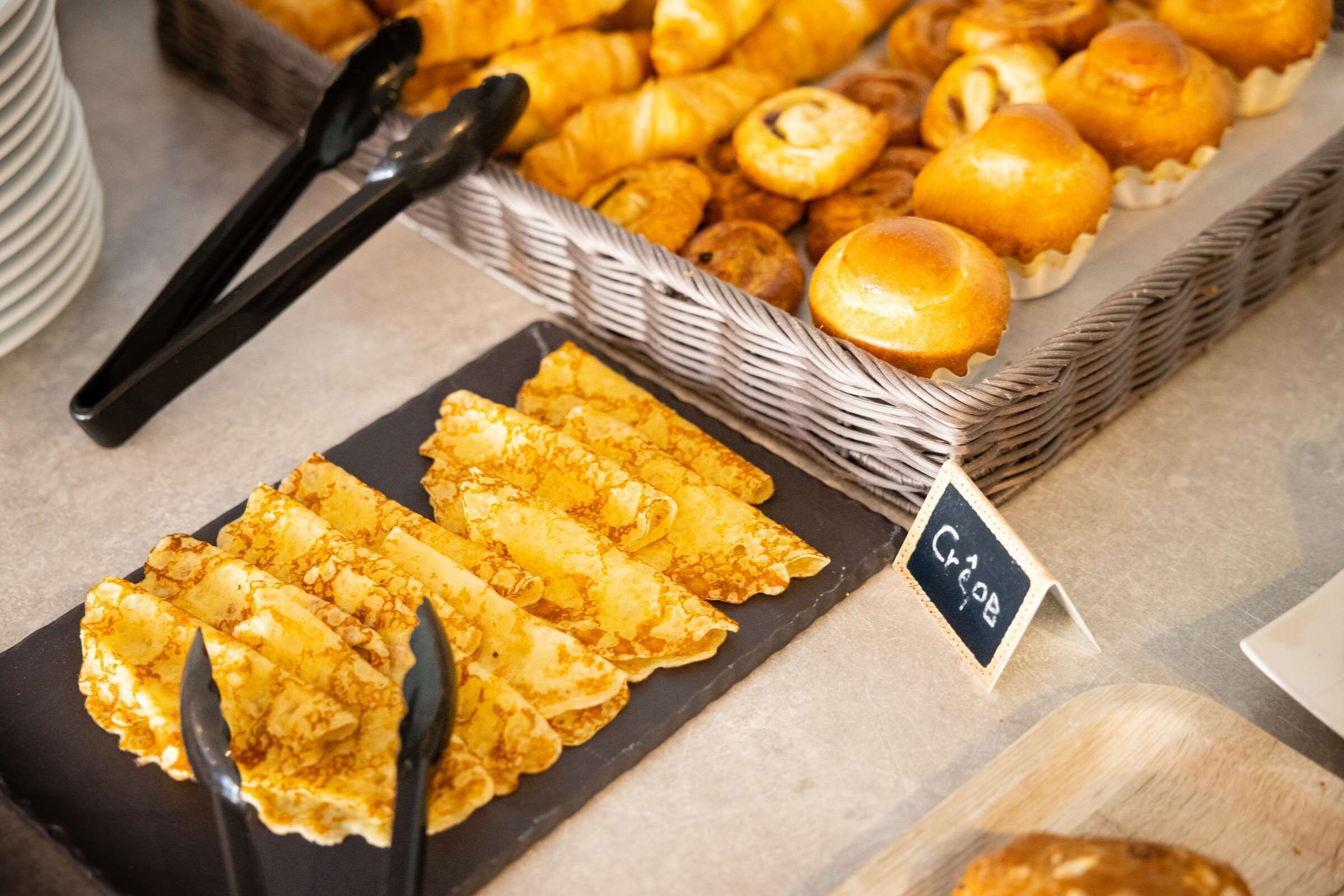 A buffet with various pastries and crepes.