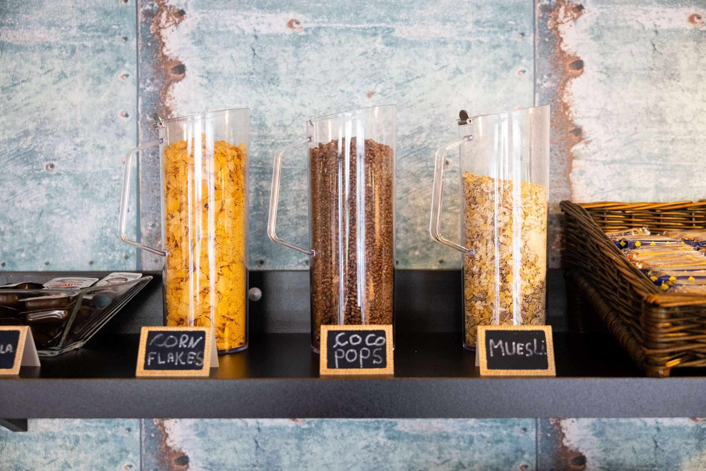 Three glass containers labeled with different types of cereal on a shelf.