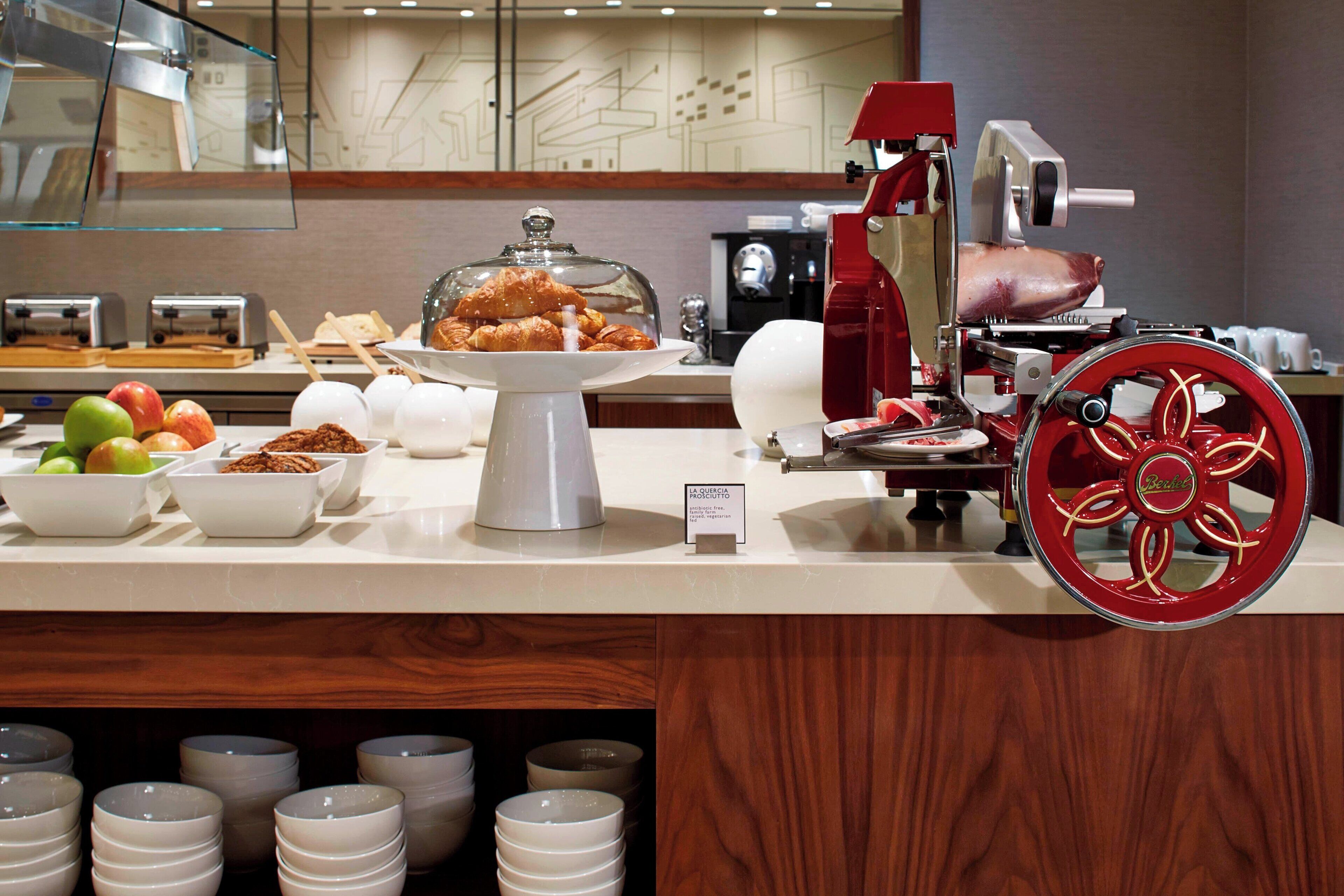A buffet area with a variety of food items, including fruits, pastries, and a meat carving station.