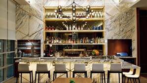 A bar area with marble walls, multiple shelves of liquor bottles, and a central chandelier. - AC Hotel by Marriott Portland Downtown, OR (Portland)