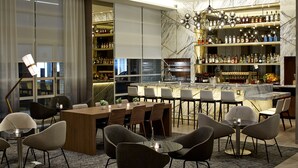 A modern bar area with a marble countertop, multiple seating arrangements, and a variety of liquor bottles. - AC Hotel by Marriott Portland Downtown, OR (Portland)