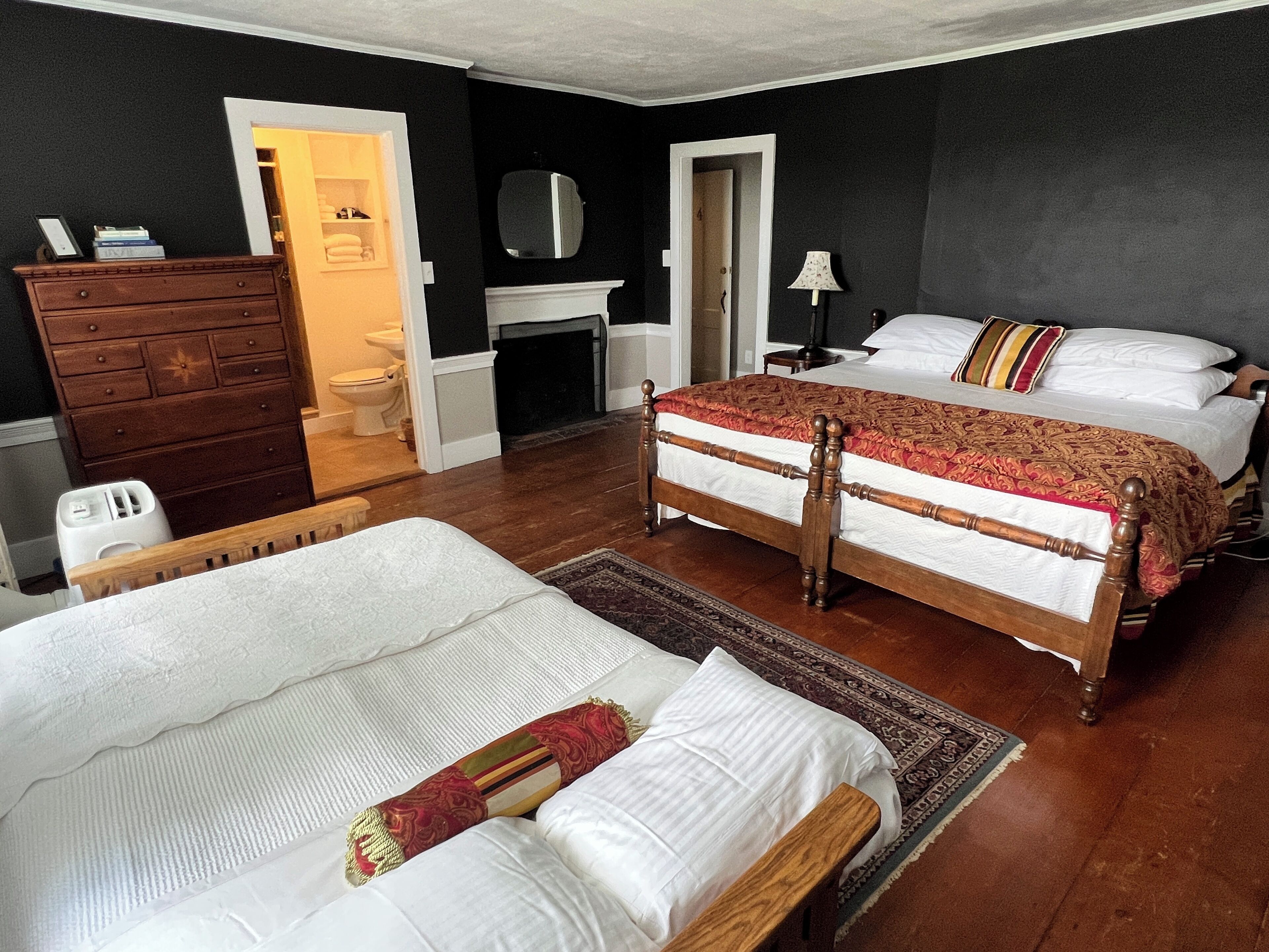 A hotel room with two beds, a dresser, a mirror, and a bathroom visible through an open door.